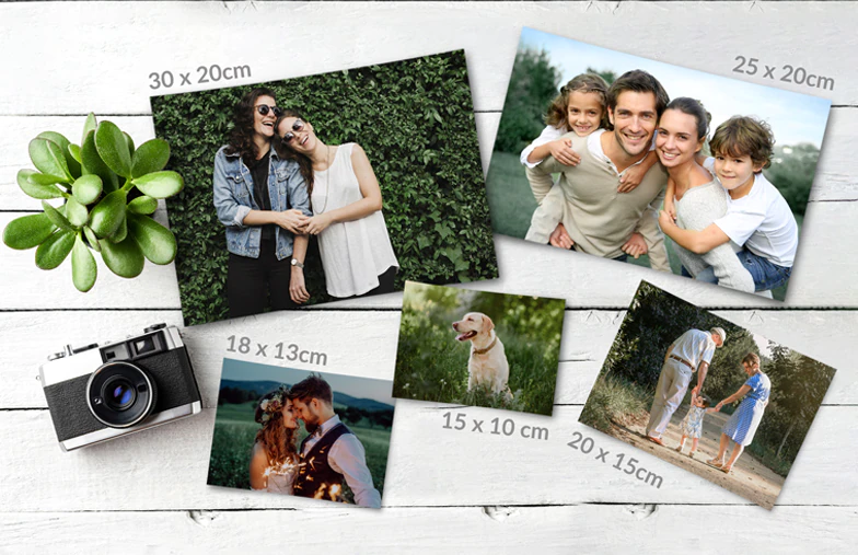 Fotoausdrucke von Printerpix|Stapel von individuell gestalteten Fotoabzügen vom Online-Fotodruckdienst Printerpix|Fotoabzüge|Fotoabzüge|Hände halten einen Fotoabzug von drei Kindern im Urlaub|Verschiedene Größen von Online-Fotoabzügen von Familienfotos, die mit dem Mobiltelefon aufgenommen wurden|||||