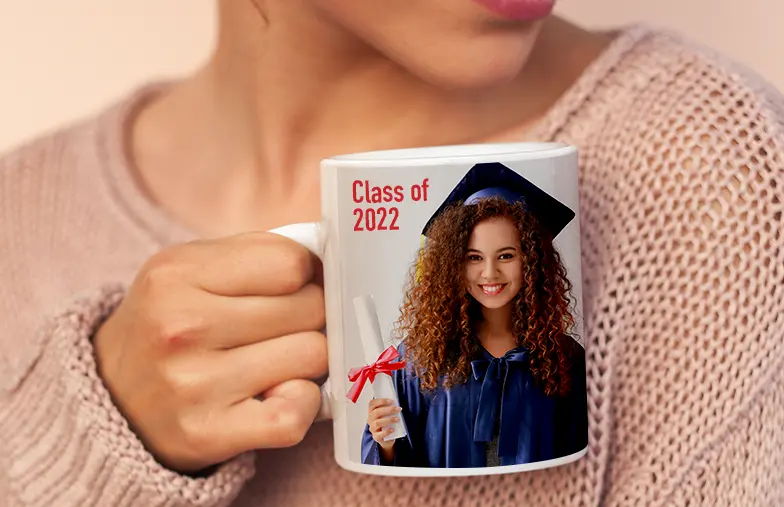 ["Personalised photo mugs by Printerpix", "Graduation mug with personalised design and 'Dad' text", "Personalised photo mug with picture of a crawling baby in an animal onesie", "Mother and daughter holding custom-designed photo mugs with family photos", "Kissing couple with personalised mugs with text", "Personalised photo mug with your own photo of your dog", "", "", "", ""]||||||||||