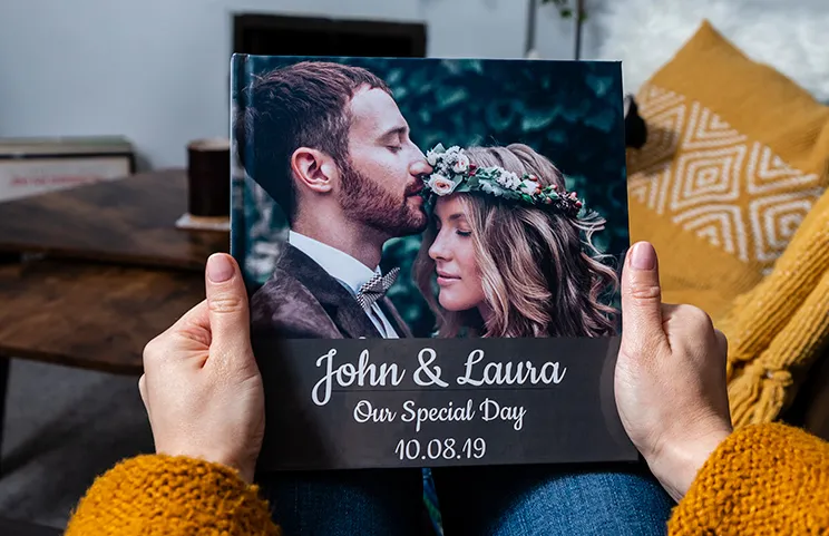 ["Hardcover Personalised Photo Books by Printerpix", "Custom-printed Printerpix photo album with hardcover and large photos of an older couple", "Personalised photo albums with romantic images of a couple and photo cover", "Family photo album with custom-printed cover and family name", "Pet and woman looking at personalised family photo album with custom design", "Two people looking at Printerpix photo book with wedding photos and bride", "", "", "", "", ""]||||||||||