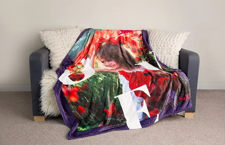 A personalised Printerpix mink blanket with a child on it, draped over a sofa. The word "Love" is visible.