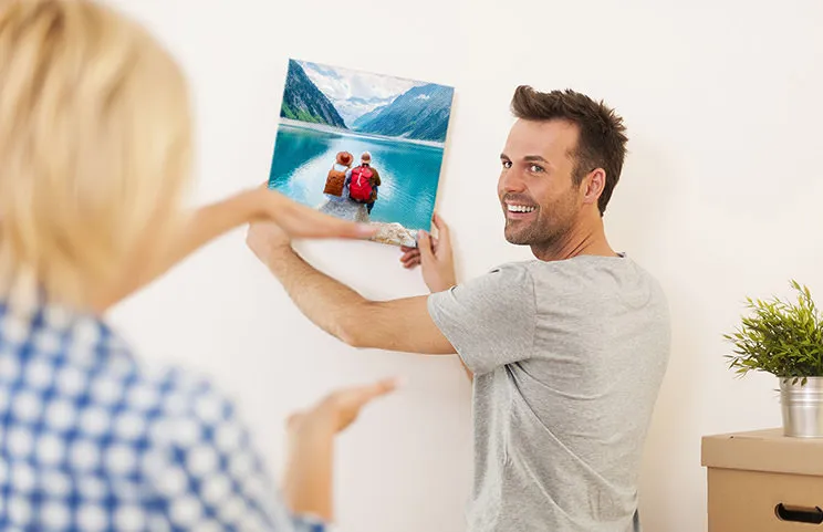 Man and woman hanging a photo canvas with a holiday picture