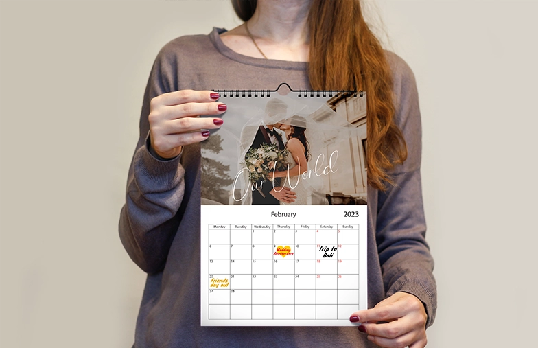 Frau schreibt auf A4 personalisiertem Wandkalender von Printerpix mit Weihnachtsfoto