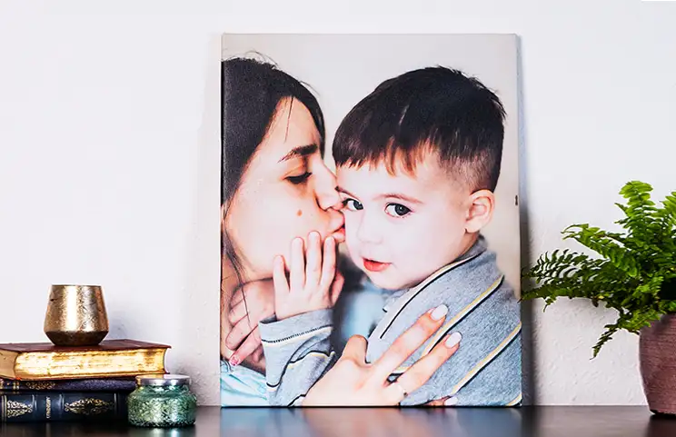Mother lovingly kissing her little son on canvas print