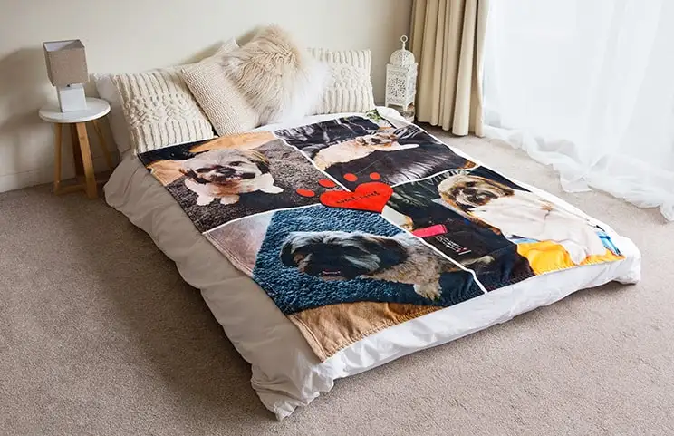A soft Printerpix mink-touch blanket with a dog collage design spread out on a bed.