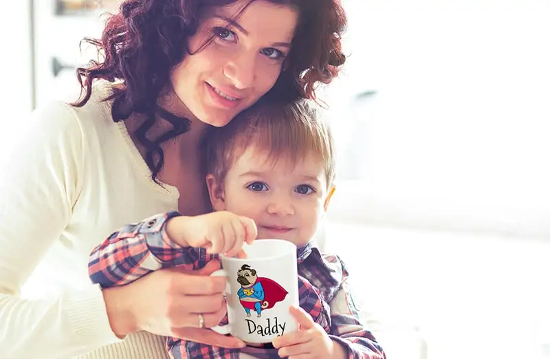 Mum and Baby Holding a Customised Mug with Printerpix Cartoon Design with Dad Text