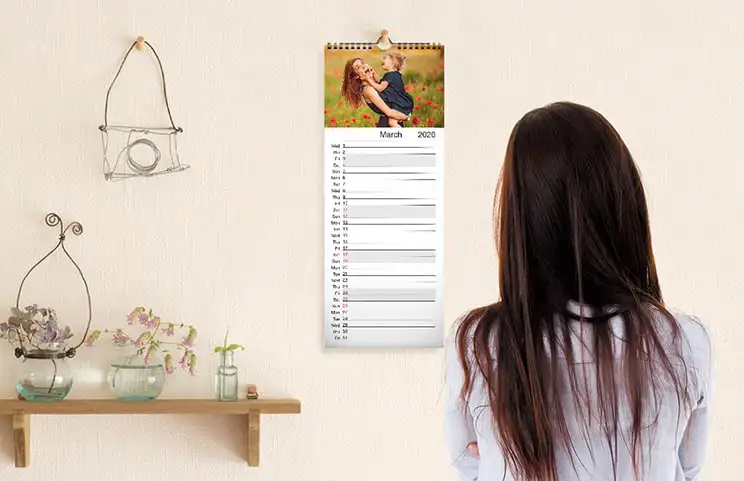 Küchenkalender an Küchenwand mit Familienurlaubsfotos aufgehängt