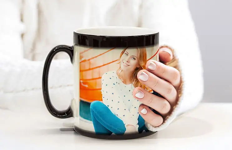 Couple holding two heat-changing magic mugs with personalized text from Printerpix