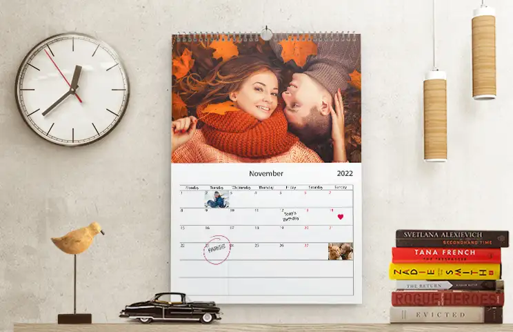 Romantic couple in the living room with a personalised 2020 wall calendar featuring an engagement photo