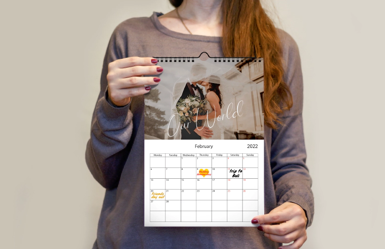 Romantic couple in living room with personalized 2020 wall calendar featuring proposal photo