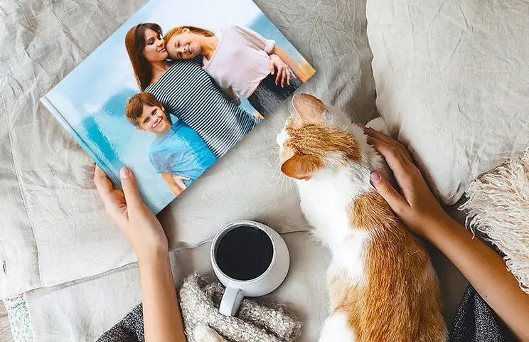 Haustier und Frau betrachten personalisiertes Familienfotobuch mit individuellem Design